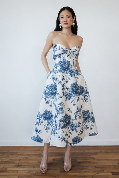 Woman wearing a strapless floral dress with blue and white pattern on a plain background