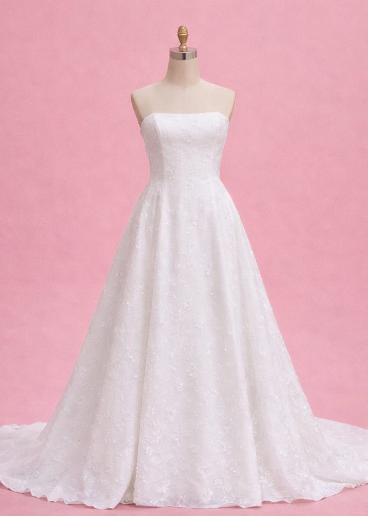 White strapless wedding dress on a mannequin against a pink background