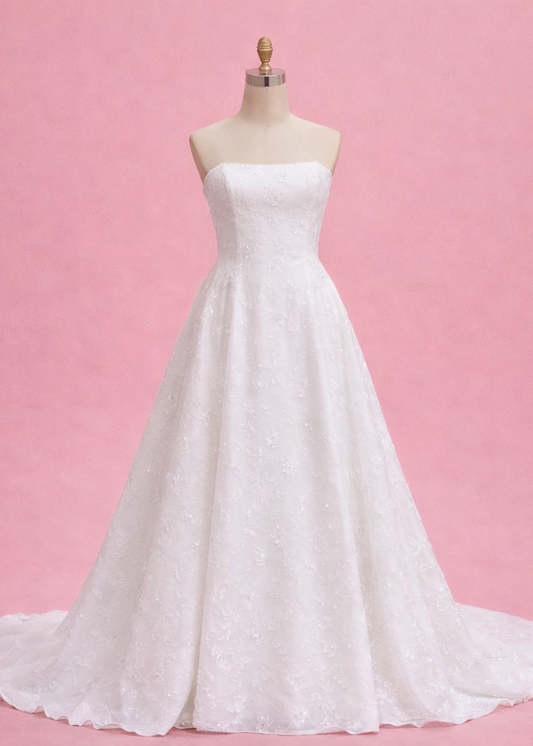 White strapless wedding dress on a mannequin against a pink background