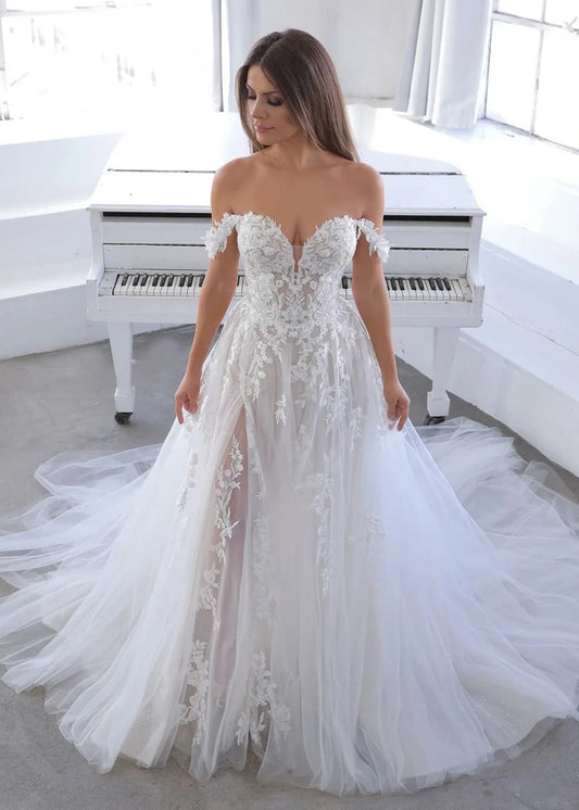 Woman in a white wedding dress standing in front of a white piano.