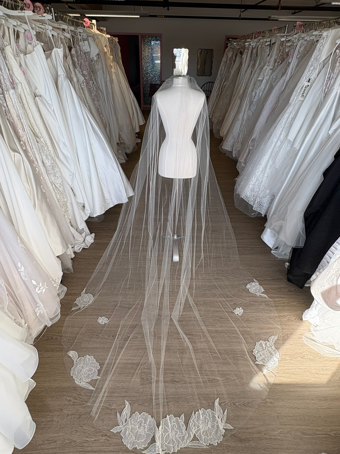 Long wedding veil with floral lace details on a mannequin in a bridal gown store in Ottawa Ontario