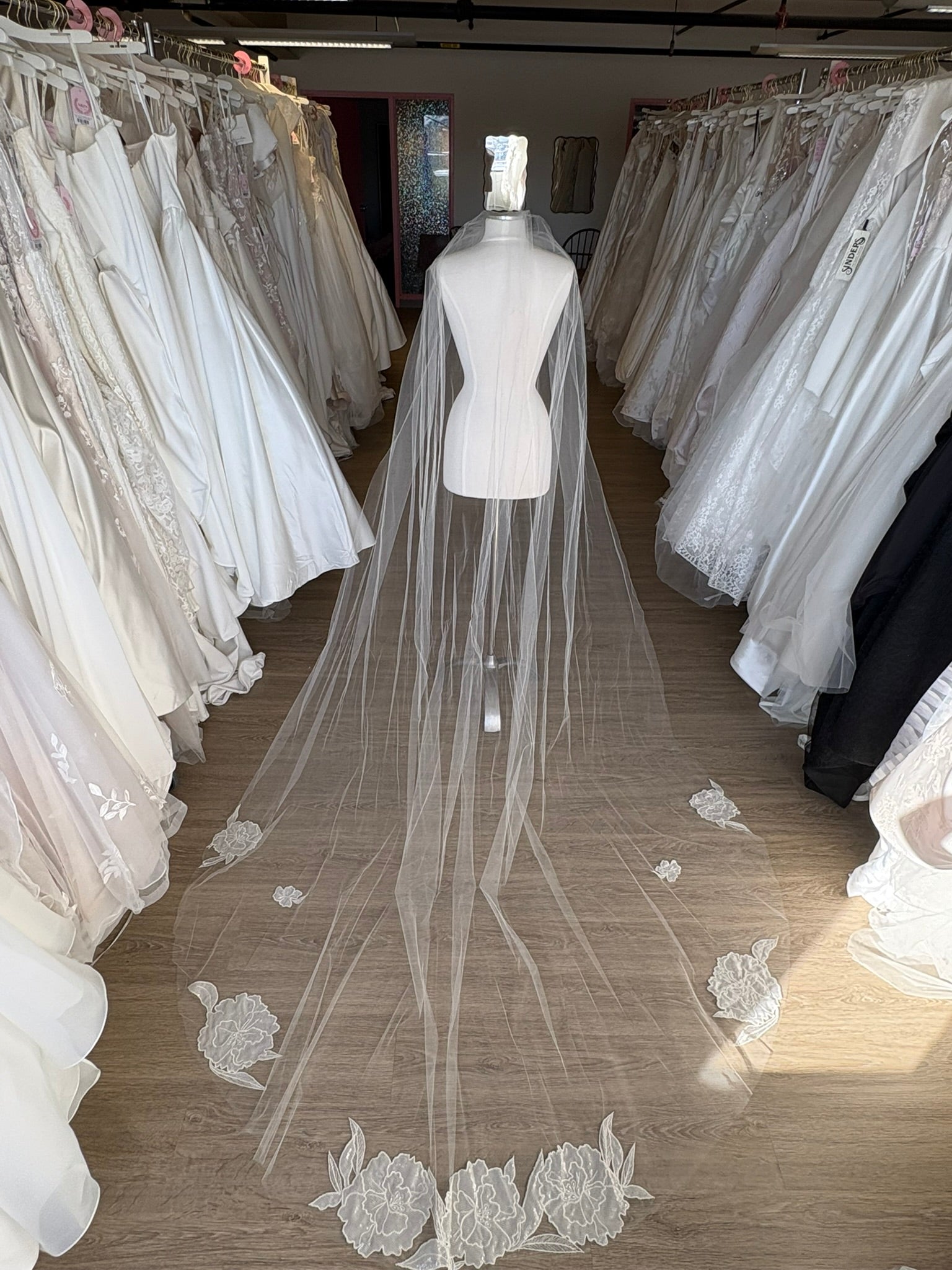 Long wedding veil with floral lace details on a mannequin in a bridal gown store in Ottawa Ontario