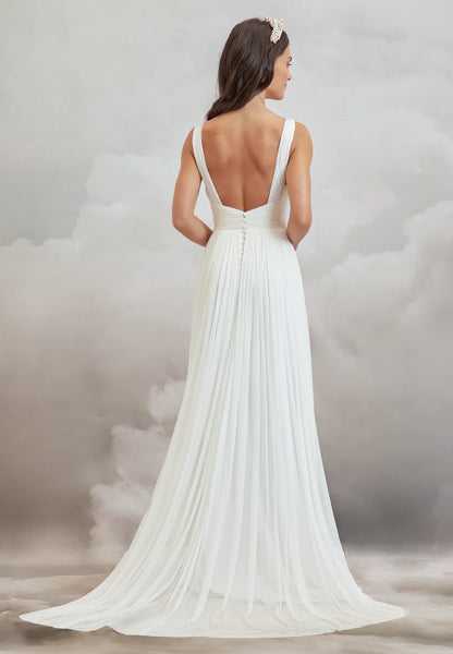 Woman wearing a white wedding dress with a flowing train against a cloudy sky background