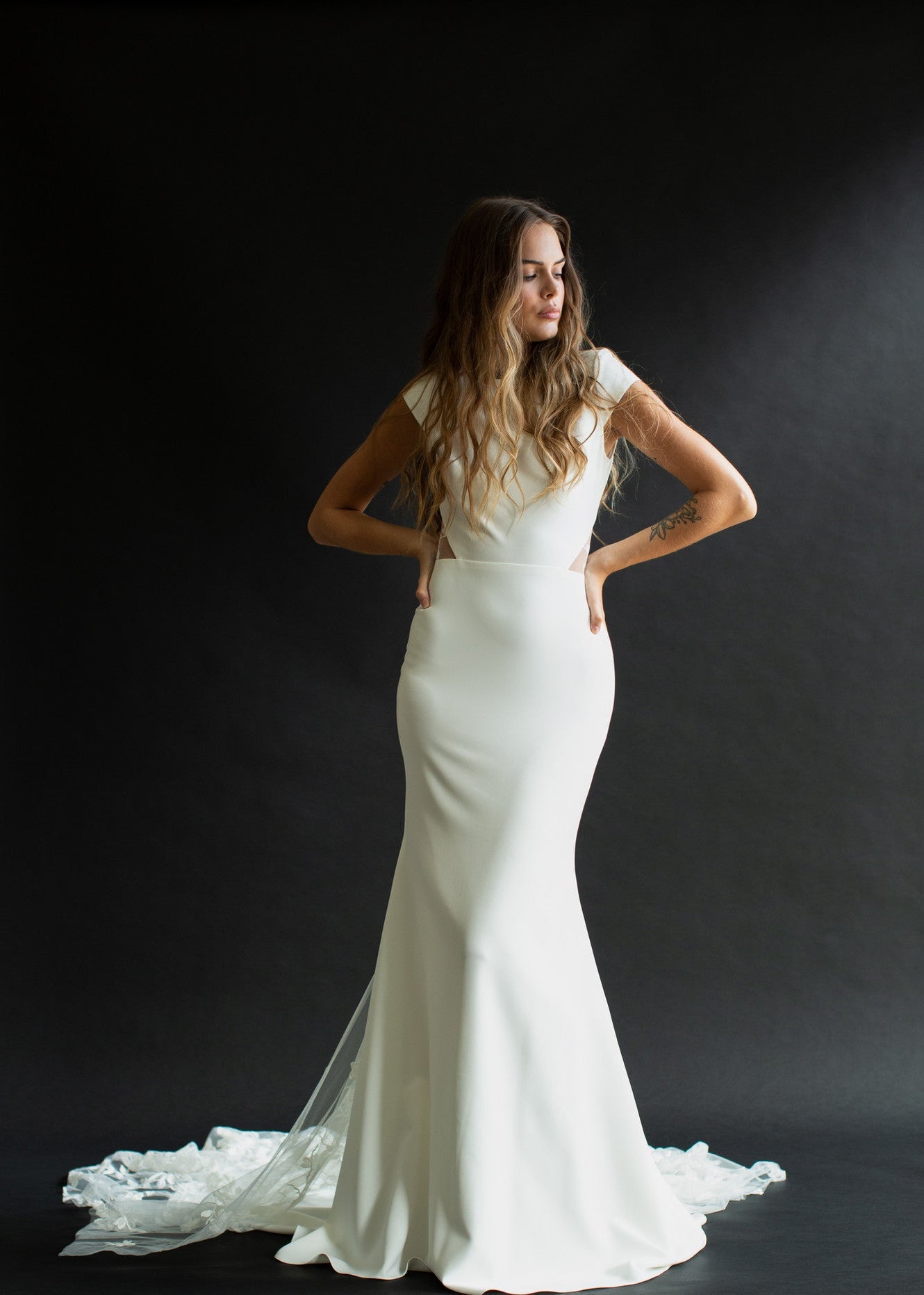 Brie is classic and timeless. Made of stunning crepe fabric, she has a bateau neckline falling into small cap sleeves. Her fitted silhouette lows into a gorgeous lace train, with a keyhole back.