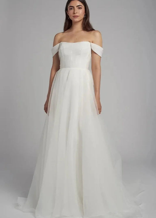 The Bronte bridal gown is cut in our lighter than air pebbled organza fabric. The flattering scoop neck is accented by the beautifully pleated bodice and elegantly draped sleeves which can be removed to create a strapless look. The full A line skirt lends a whimsical yet dramatic feel to this timeless gown.