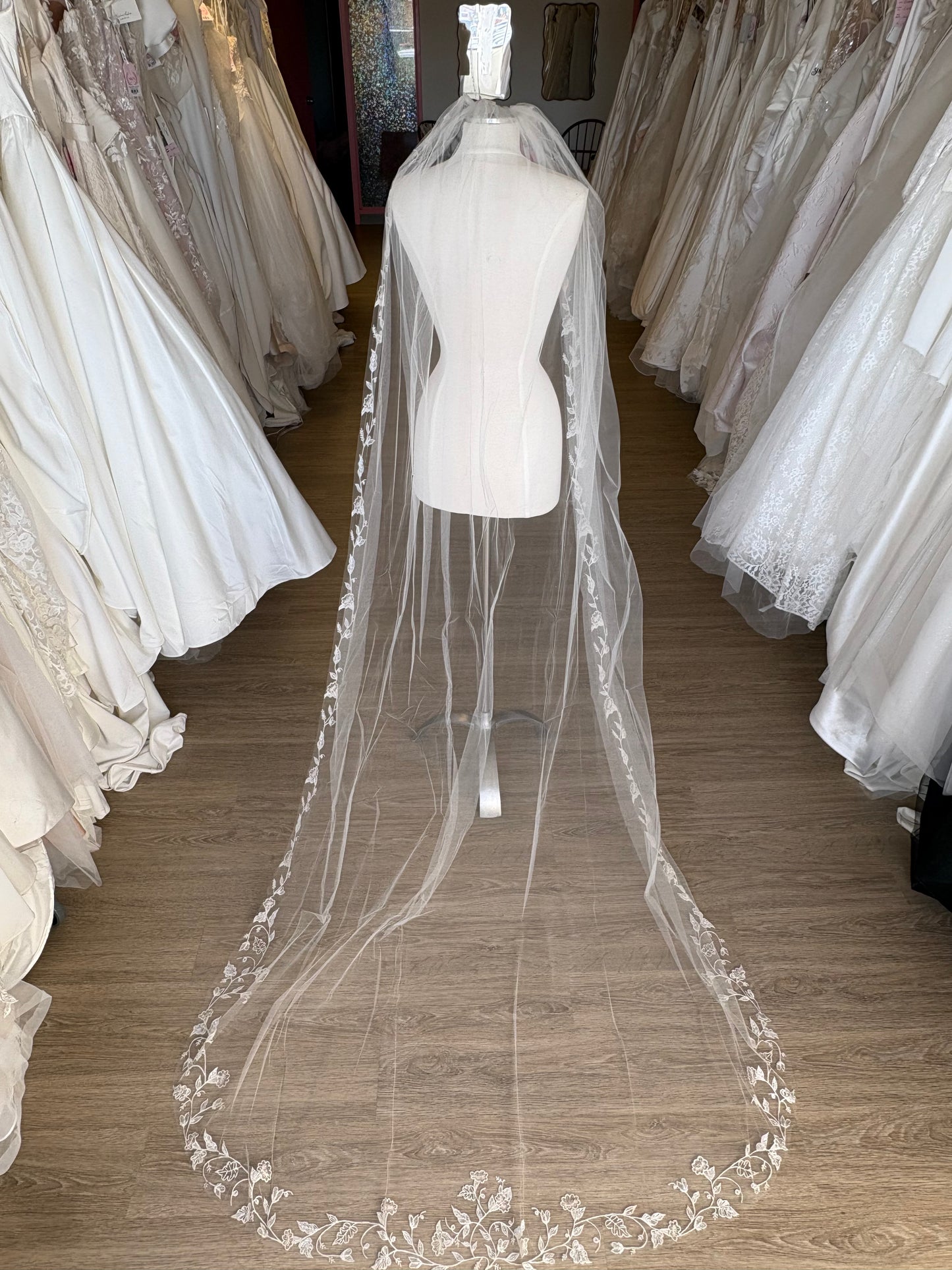 Chapel Length Floral Veil with embroidered vine and floral edges, raw edge on a mannquein at a bridal shop in ottawa