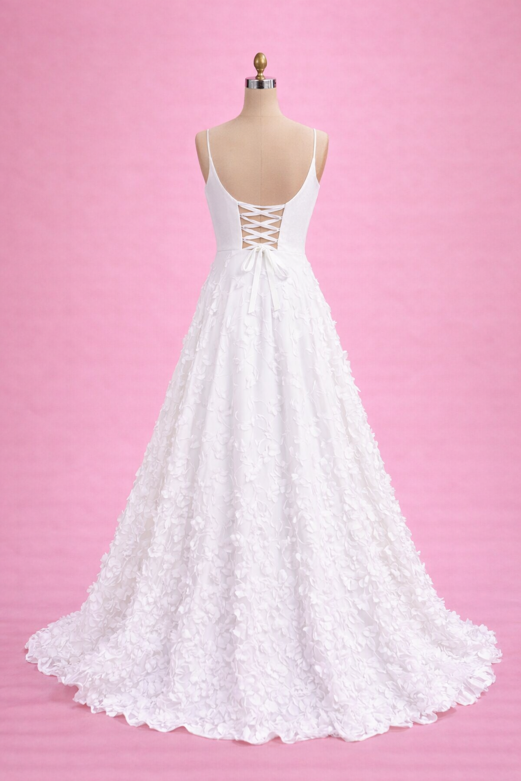 White lace wedding dress on a mannequin against a pink background