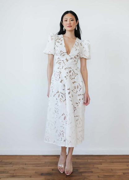 Woman wearing a white lace dress against a plain background