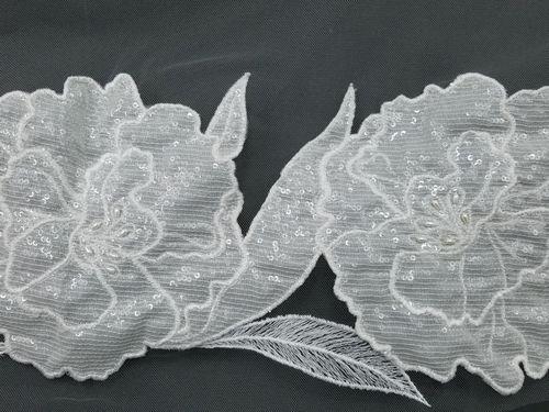 Decorative fabric trim with floral patterns and sequins on a black background