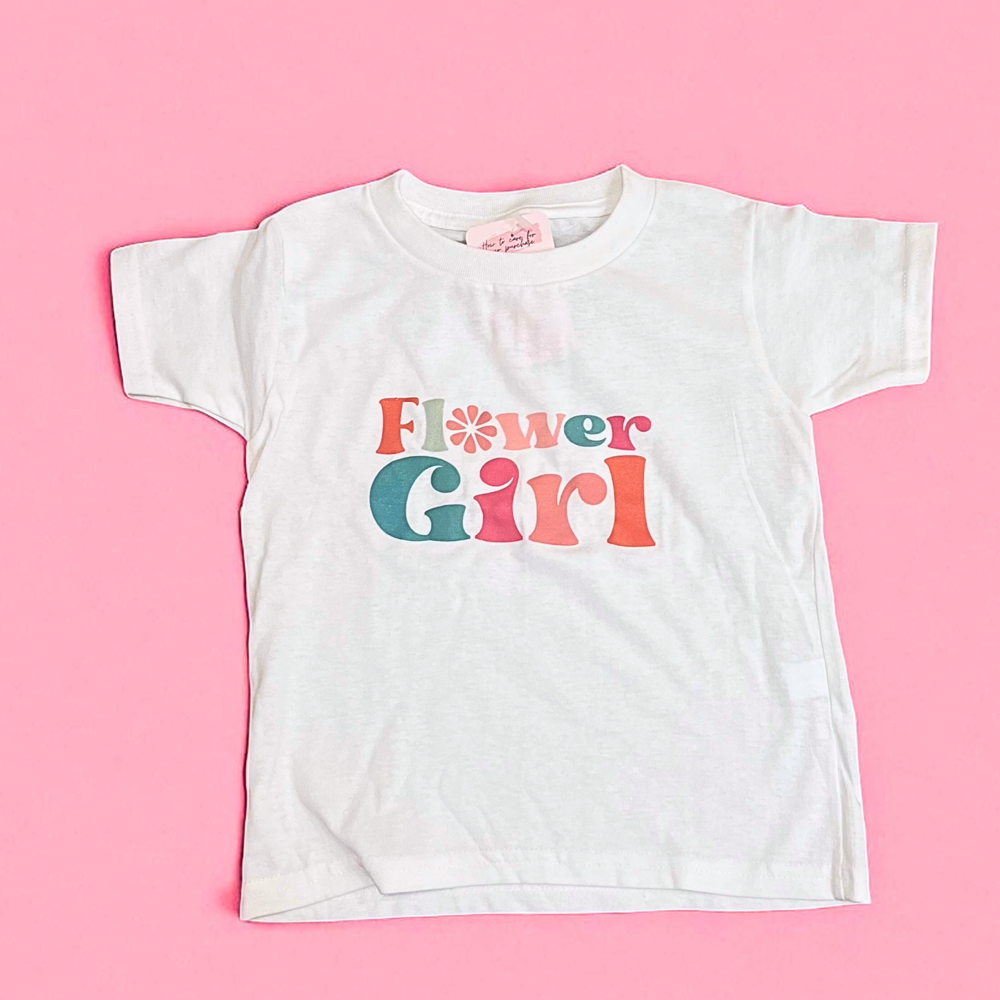 White t-shirt with 'Flower Girl' text on a pink background
