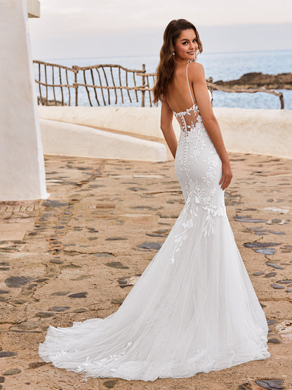 Woman in a white wedding dress standing on a stone path with ocean view