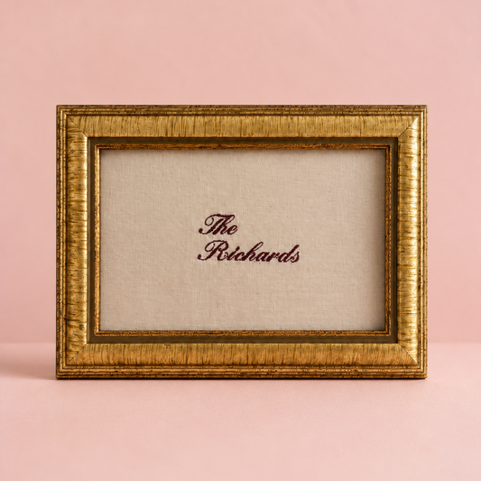Gold-framed picture with 'The Richards' text on a pink background. A linen artwork embroidery gift