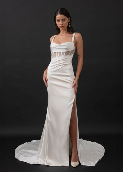 This minimalist gown is made from a stretch satin with an exposed corset lined with glitter mesh that catches the light in all the right places. Her sweetheart illusion bodice features exposed boning and asymmetrical draping from the waistline that is ruched to accentuate your curves. Her fitted slimline skirt hugs the body with a left leg hemline split for a touch of skin