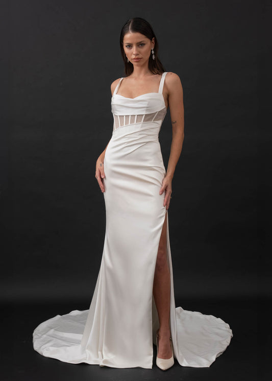 This minimalist gown is made from a stretch satin with an exposed corset lined with glitter mesh that catches the light in all the right places. Her sweetheart illusion bodice features exposed boning and asymmetrical draping from the waistline that is ruched to accentuate your curves. Her fitted slimline skirt hugs the body with a left leg hemline split for a touch of skin