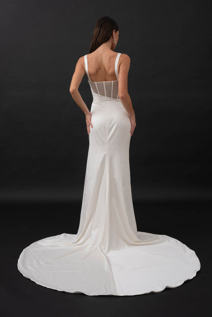 This minimalist gown is made from a stretch satin with an exposed corset lined with glitter mesh that catches the light in all the right places. Her sweetheart illusion bodice features exposed boning and asymmetrical draping from the waistline that is ruched to accentuate your curves. Her fitted slimline skirt hugs the body with a left leg hemline split for a touch of skin