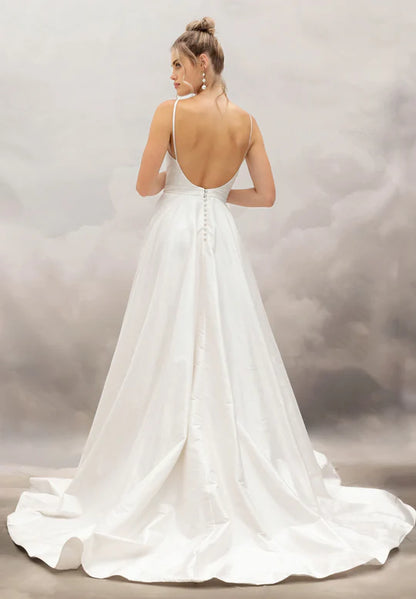 Woman wearing a white wedding dress with a open back against a cloudy sky background