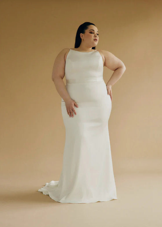 A satin mermaid wedding gown with a high neck, low back silhouette + back buttons - a full body front view
