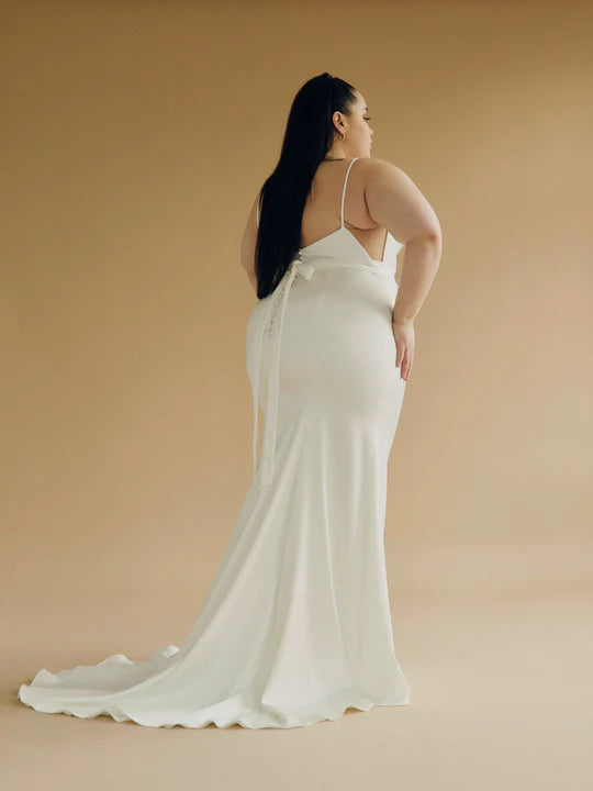 A satin mermaid wedding gown with a high neck, low back silhouette + back buttons - a full body back view