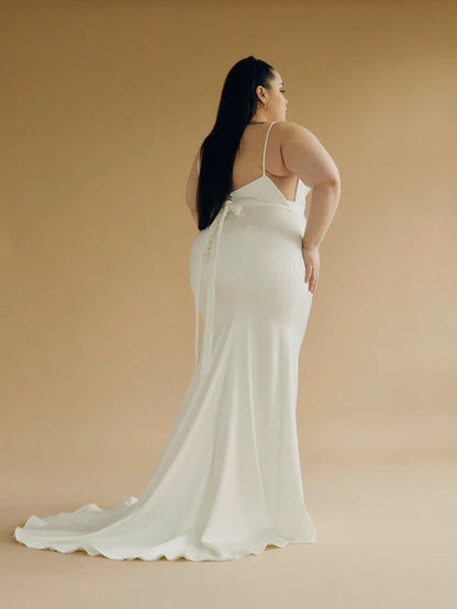 A satin mermaid wedding gown with a high neck, low back silhouette + back buttons - a full body back view