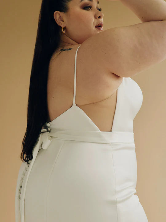 A satin mermaid wedding gown with a high neck, low back silhouette + back buttons- a close up side view