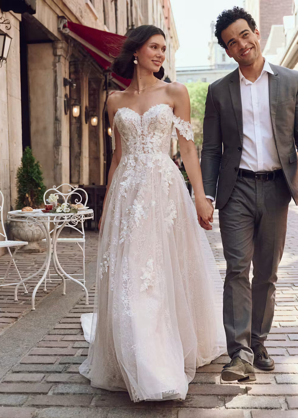 Man and woman holding hands on a street, woman in a white wedding dress