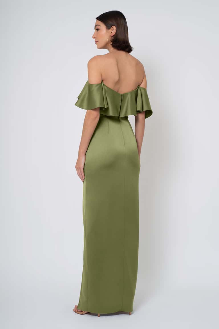 Woman wearing a green off-shoulder dress with ruffled details on a white background