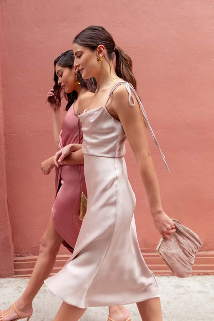 Two women walking outdoors with a pink wall in the background