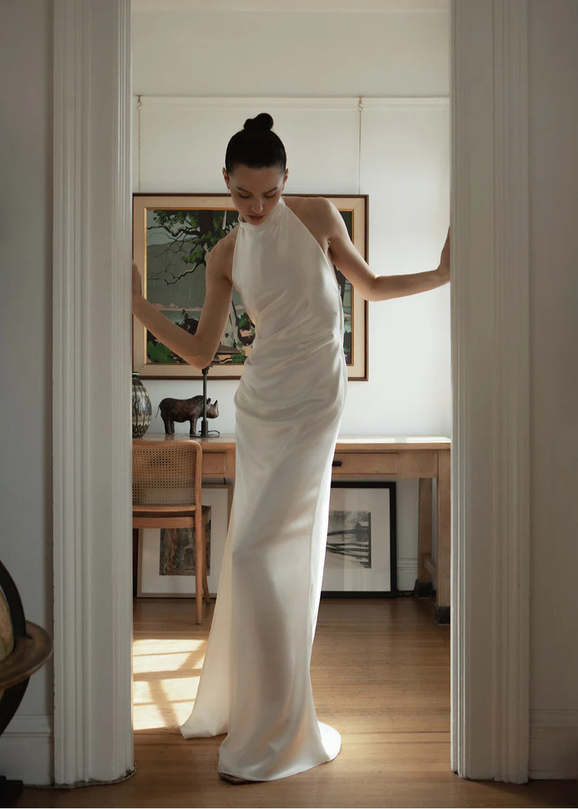 The Laurene is a bias-cut silk blend dress featuring a high collar and open back. Adorned with pleats in the front, a leg slit and jaw dropping open back design. A detachable bow in the back finished off this relaxed fit timeless gown.


The Laurene dress is classic yet modern, elegant but sexy. It will be perfect for a beach wedding, city-chic ceremony, or any wedding-related events such as elopement, rehearsal dinner, or reception.