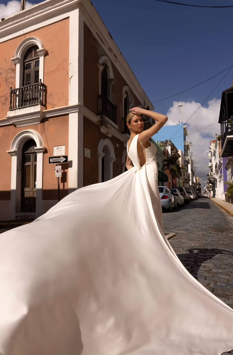Woman in a white dress standing on a street with buildings and cars in the background