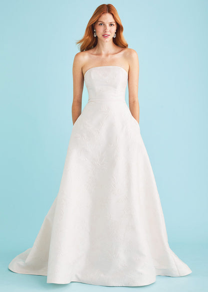 Woman wearing a strapless white wedding dress against a light blue background