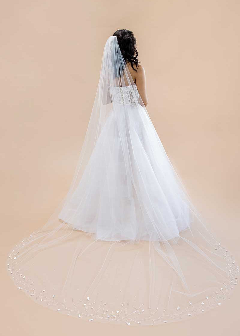 Bride wearing a long white veil with a beige background