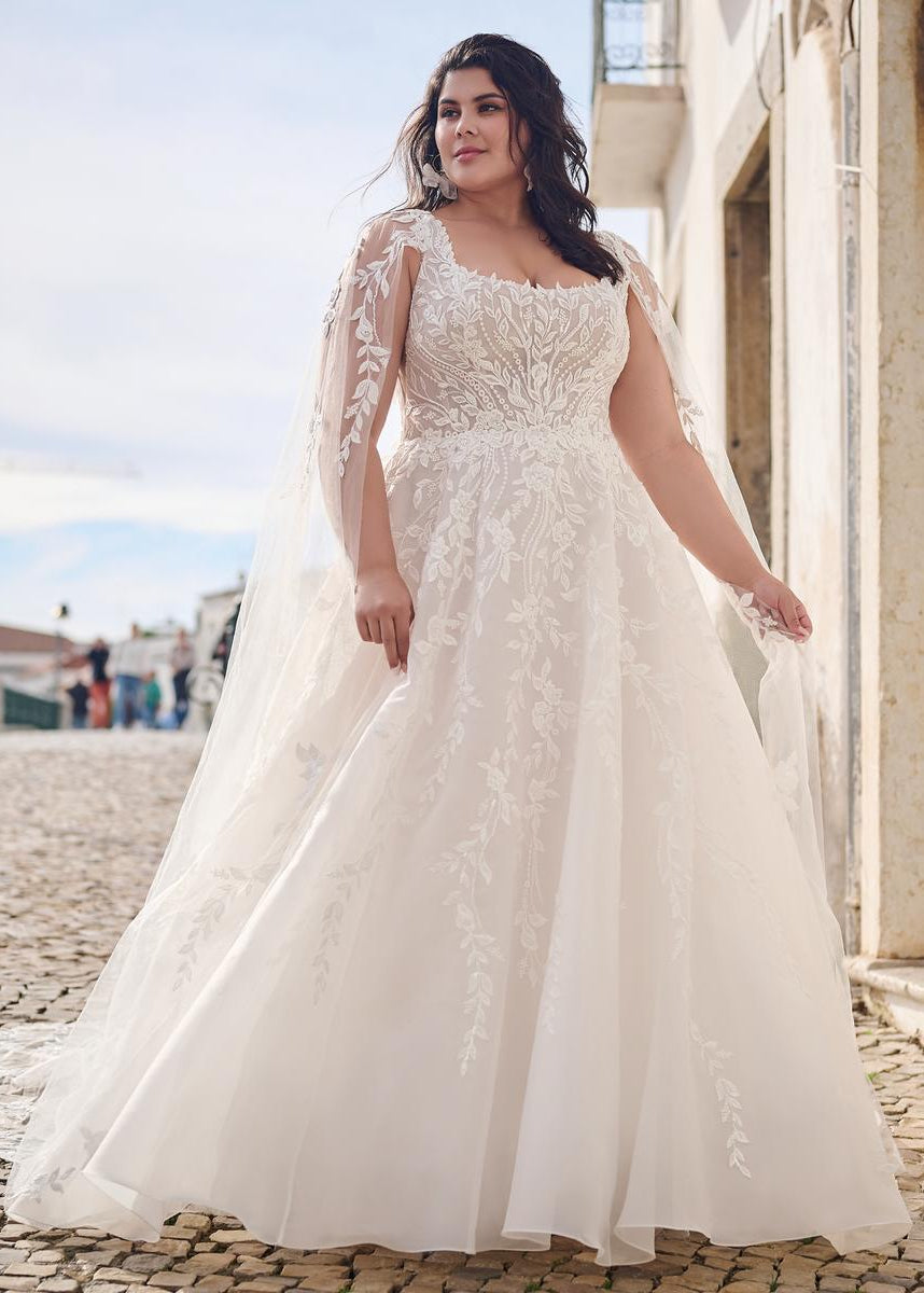 Woman in a white lace wedding dress standing on a cobblestone street.