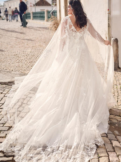 Woman in a white wedding dress with a long train on a cobblestone street.