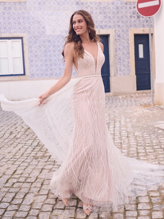Woman in a long, light-colored dress standing on a cobblestone street.