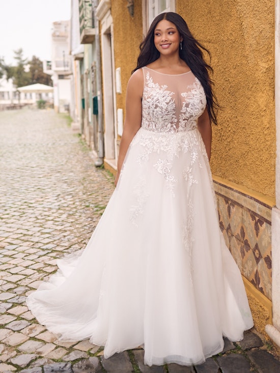 Woman in a white wedding dress standing on a cobblestone street.