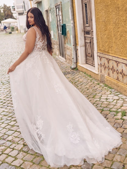 Woman in a white wedding dress standing on a cobblestone street.