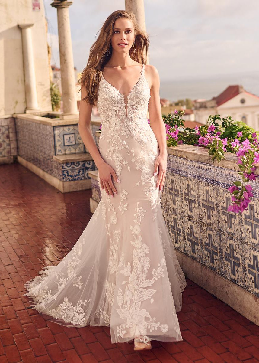 Woman in a white lace dress standing on a balcony with floral decorations.