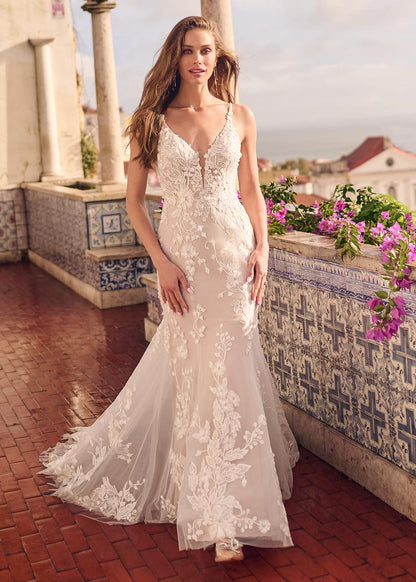 Woman in a white lace dress standing on a balcony with floral decorations.