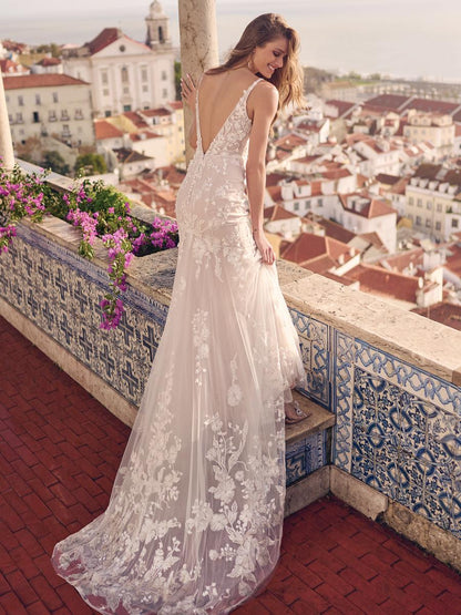 Woman in a white lace dress standing on a balcony with a cityscape view.