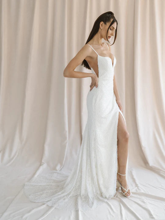 A sexy mermaid wedding gown with a cat-eye neckline, curved side slit skirt, and dazzling pearl lace - full body side view