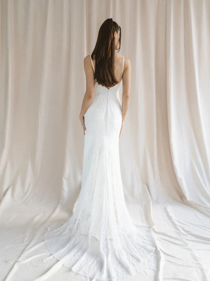 A sexy mermaid wedding gown with a cat-eye neckline, curved side slit skirt, and dazzling pearl lace - full body back view