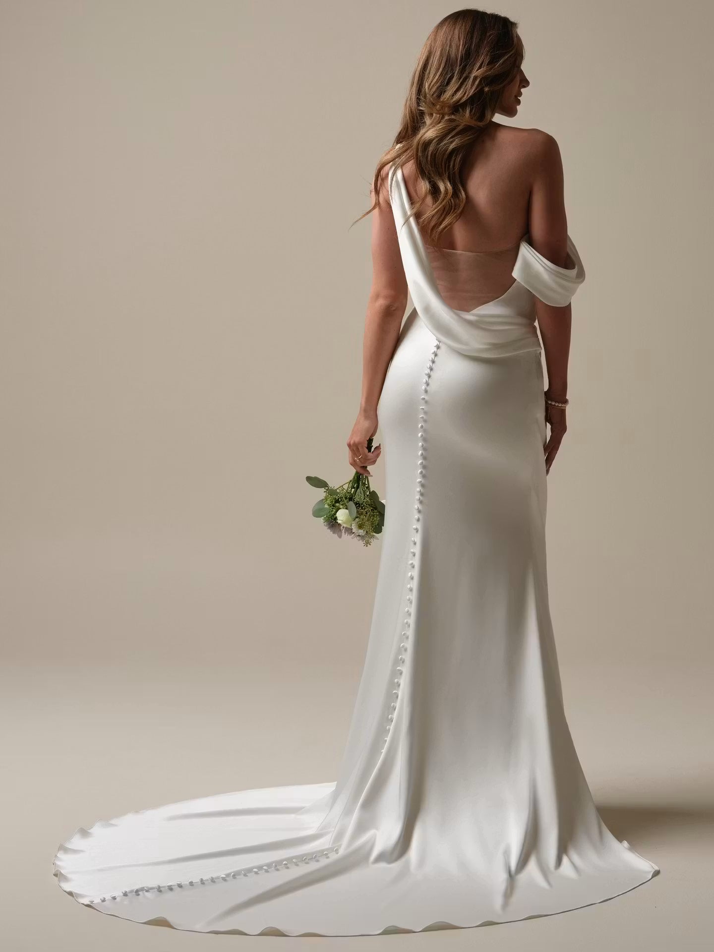 Plunging illusion V-back with draped cowl detail with an asymmetrical zipper closure with covered buttons trailing to hem at NKIN in Ottawa