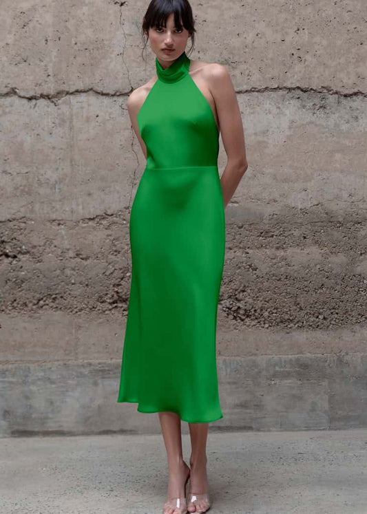 Woman wearing a green dress standing against a textured wall.