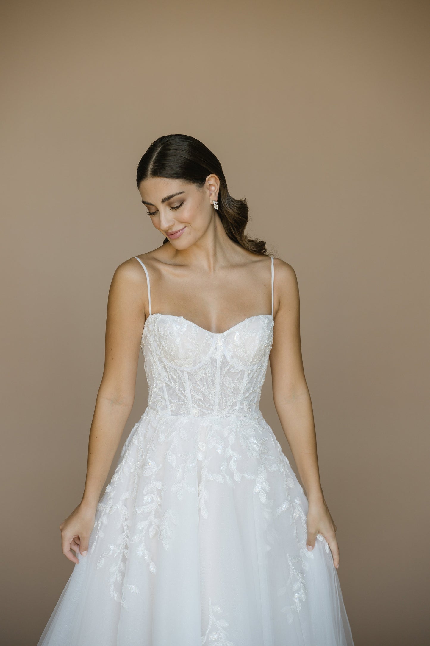 Woman wearing a white wedding dress against a beige background