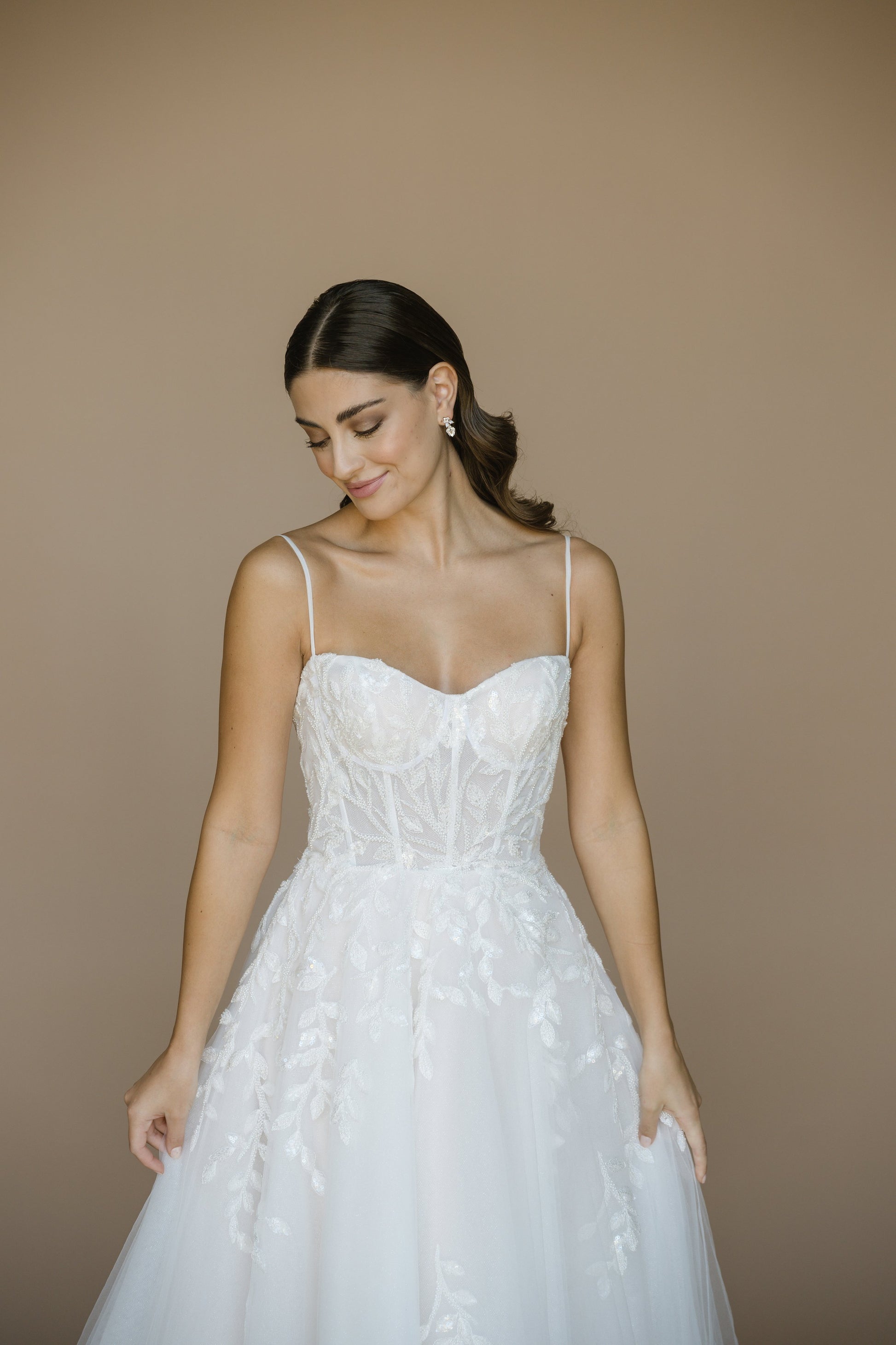 Woman wearing a white wedding dress against a beige background