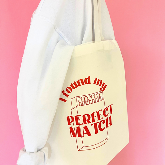 Beige tote bag with red text 'I found my perfect match' on a pink background