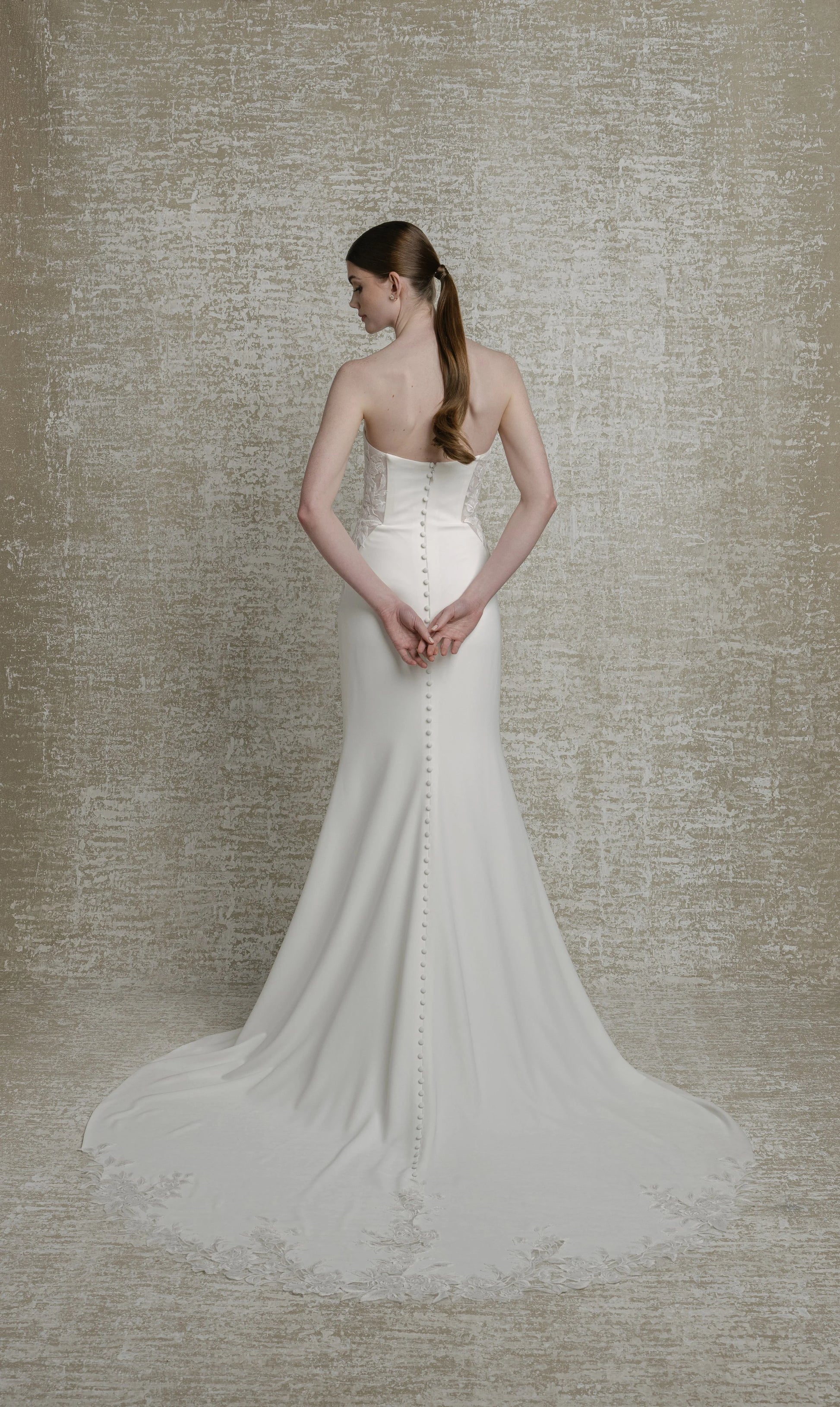 Mikado crepe, strapless sweetheart neckline with decorative boning and sequinned lace illusion cutouts, fit to flare skirt, zip closure with decorative buttons down illusion cutout chapel train. 

