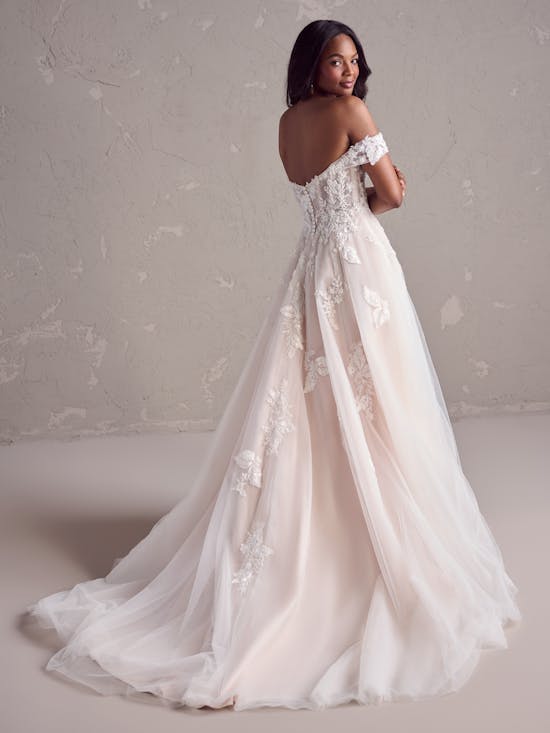 Woman wearing a white lace wedding dress against a neutral background