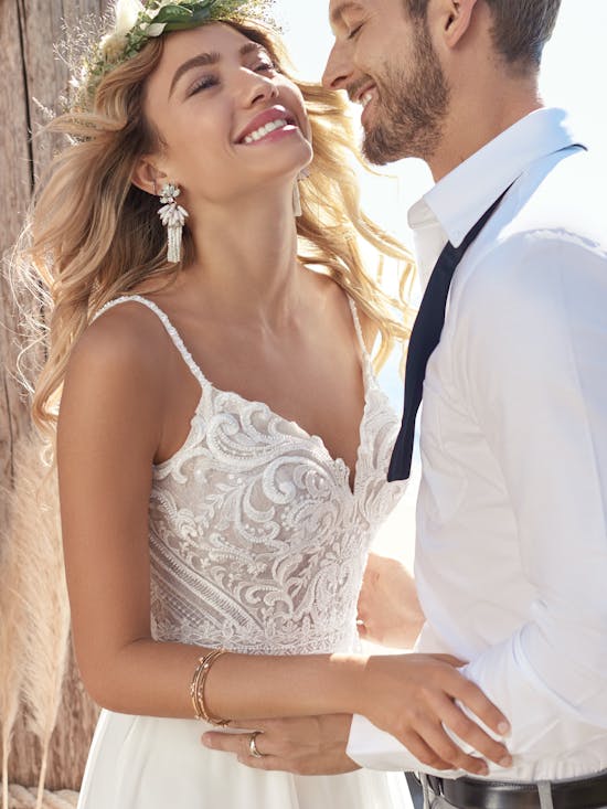 Couple in wedding attire standing close together outdoors.