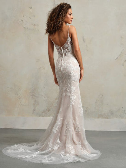 Woman wearing a white lace wedding dress with a long train against a neutral background